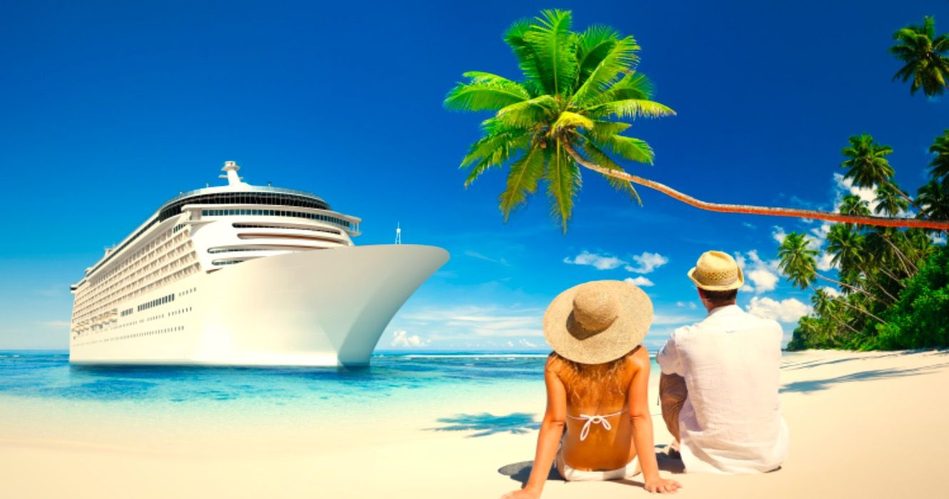 Couple sitting in the sand staring at cruise ship