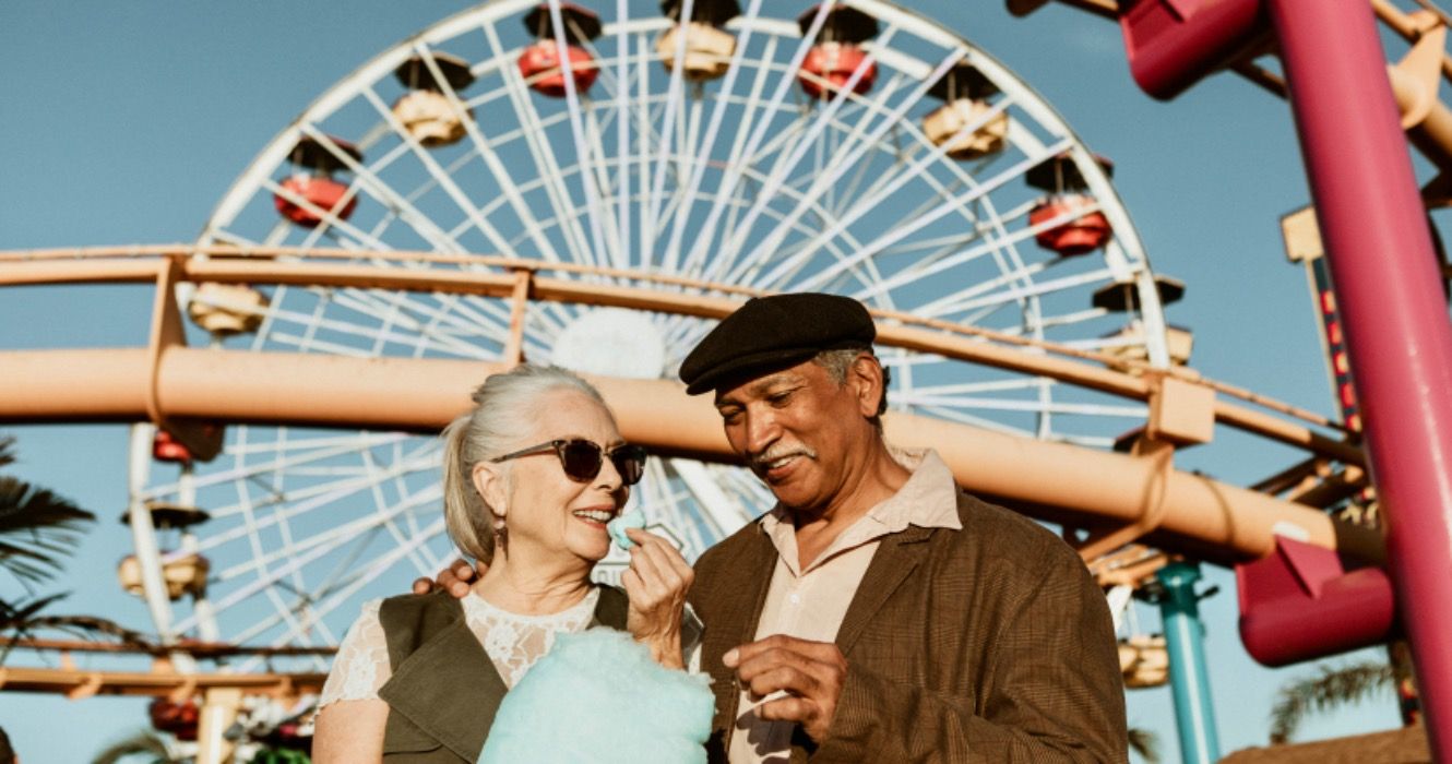 Cheerful elderly couple enjoying cotton candy at Pacific Park in Santa Monica, California