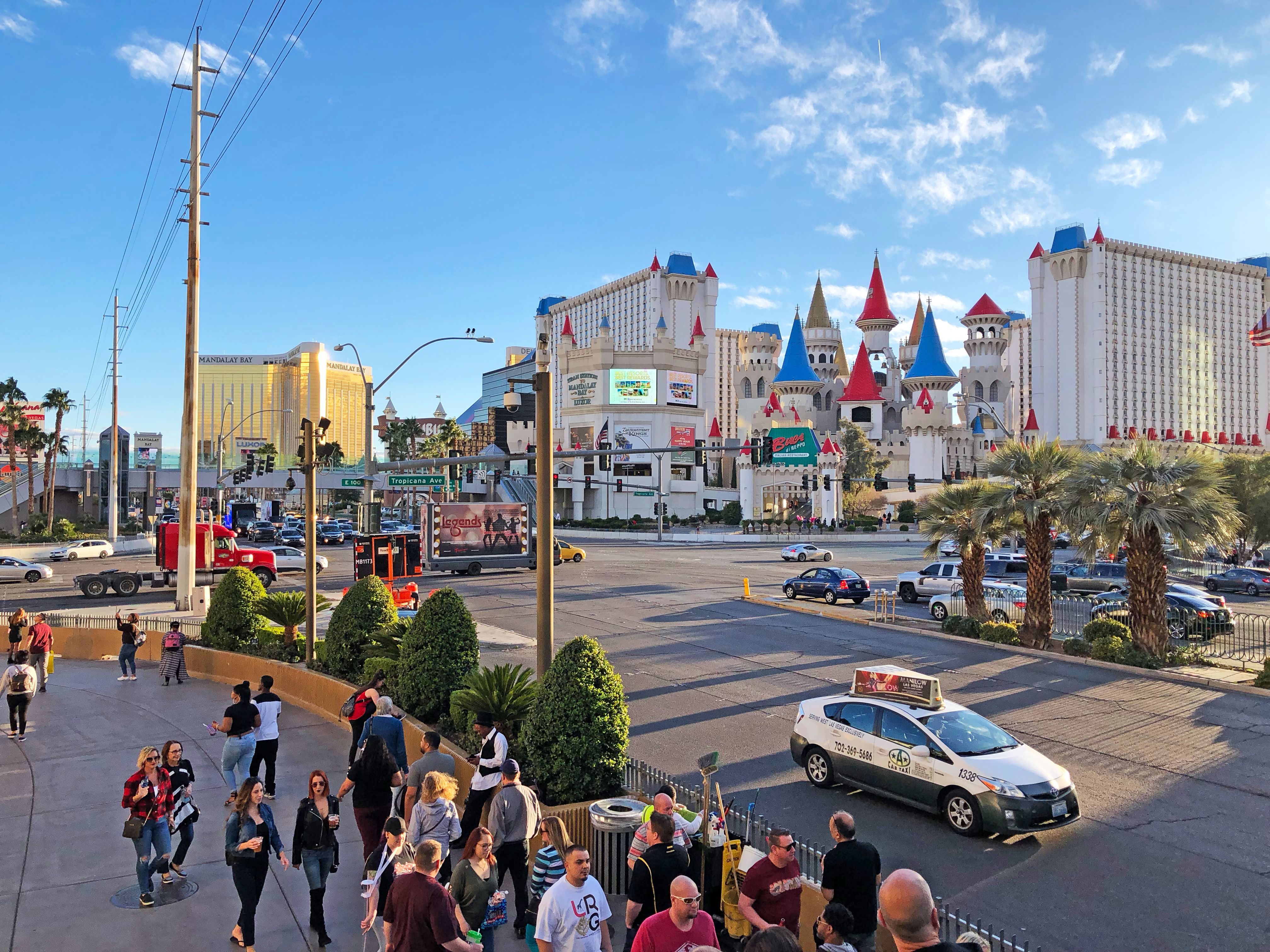 Panoramic view of the Excalibur Hotel and Casino Castle and towers with people walking on pavement.