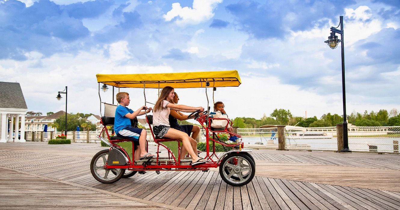 Young happy family riding a double surrey tandem bicycle on a large ocean boardwalk.