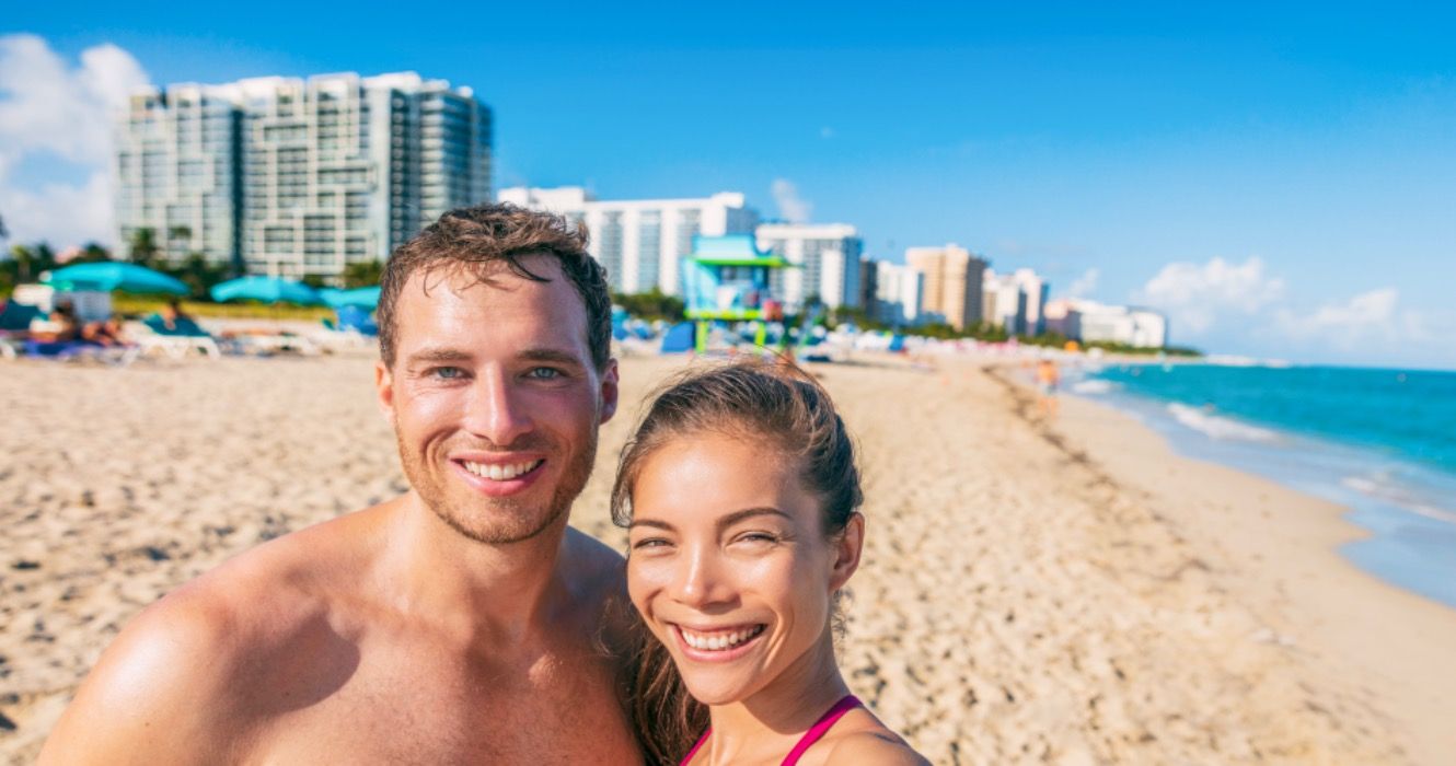 Happy couple taking fun selfie on Florida beach on travel summer vacation.