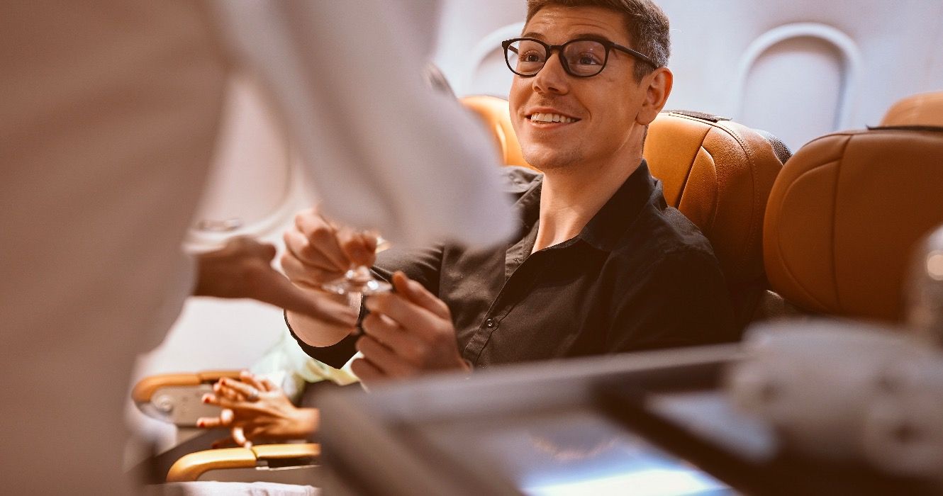 Man being served food in business class on airplane