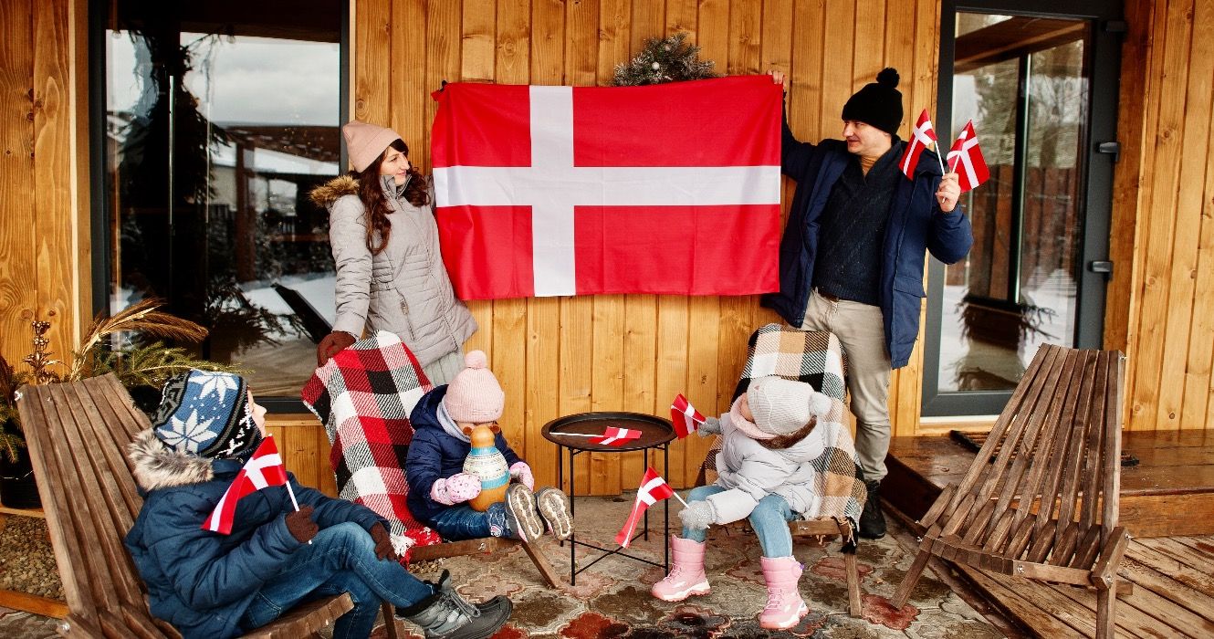 Family with Denmark flags near they wooden house. 