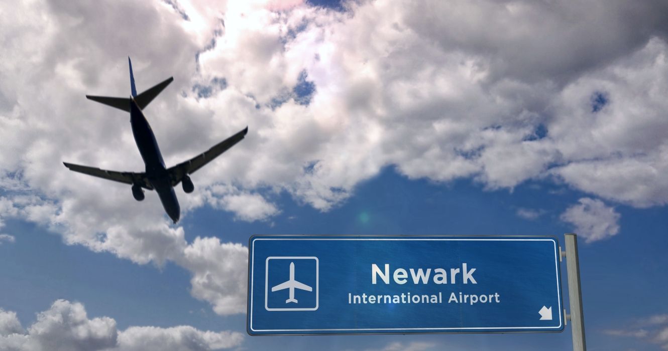 Newark International Airport sign with plane flying overhead