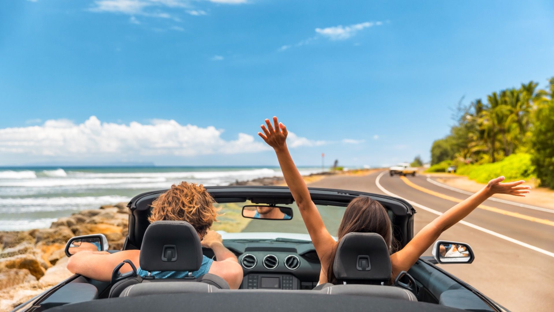 Road trip car holiday happy couple driving convertible car on summer travel Hawaii vacation.