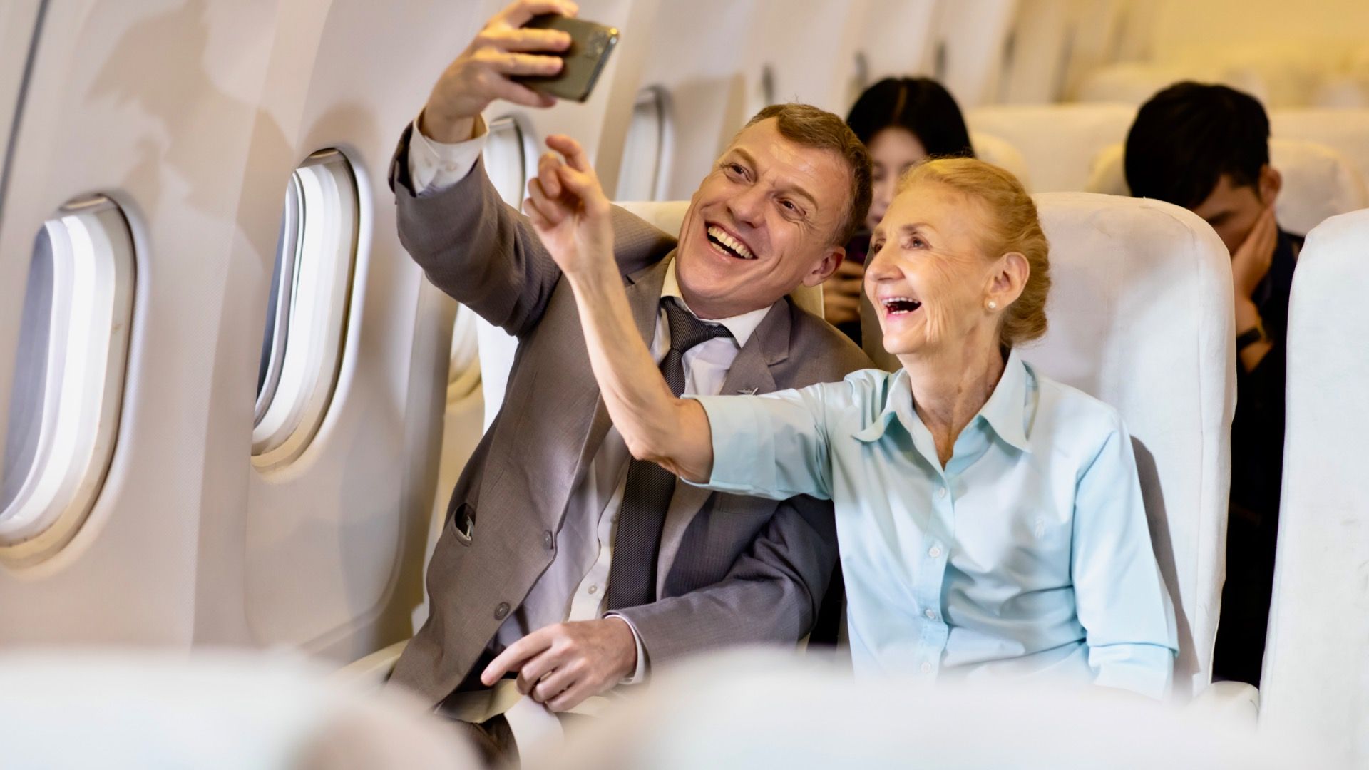 Happy Senior business man and mother passenger make selfie photo sitting in comfortable business class seat.