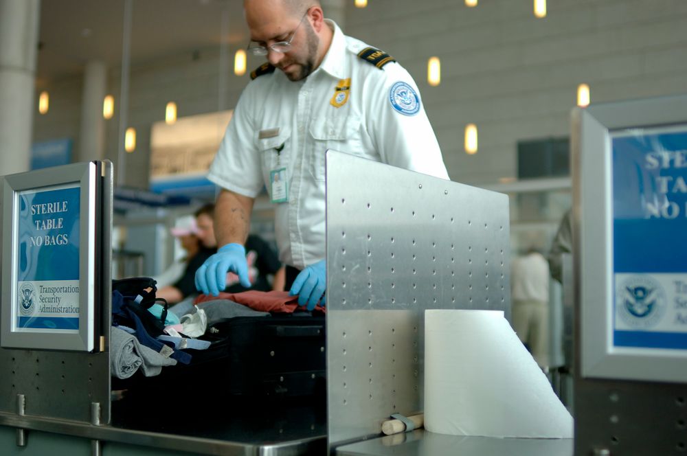 A TSA agent searches luggage at an airport