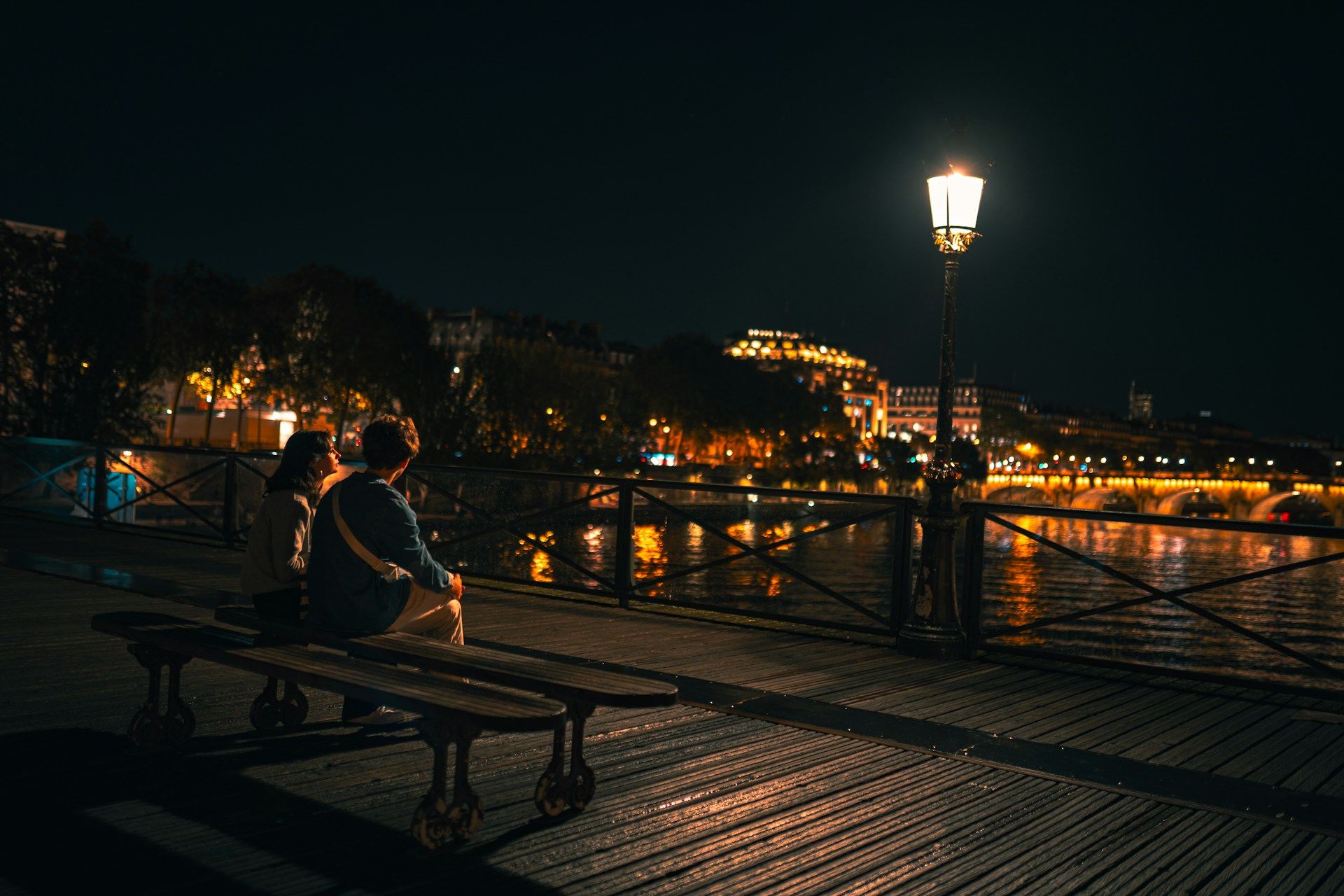 A couple sitting on a bench on the Pont des Arts Bridge, Paris