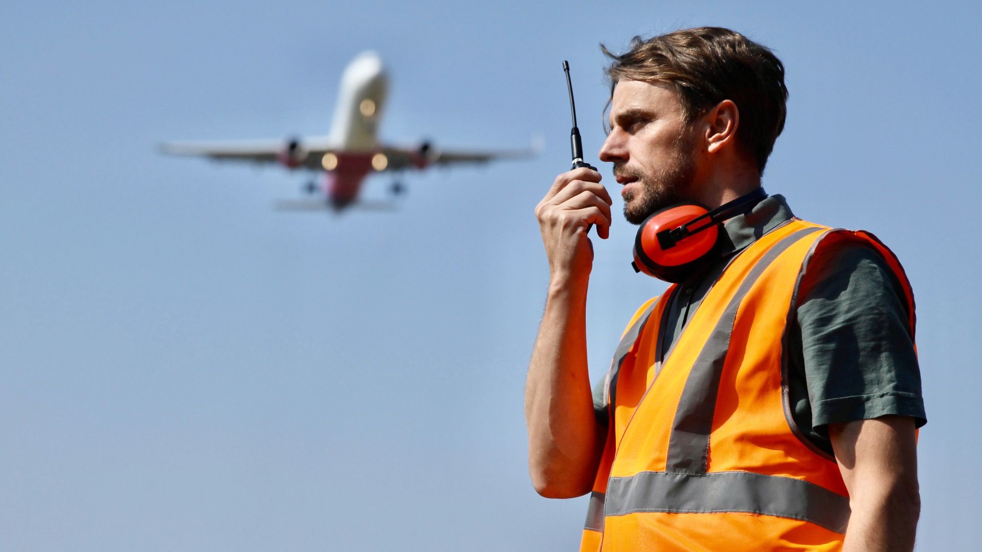 Airport Ground Worker Man Communicating Over Walkie Talkie with Air Traffic Control