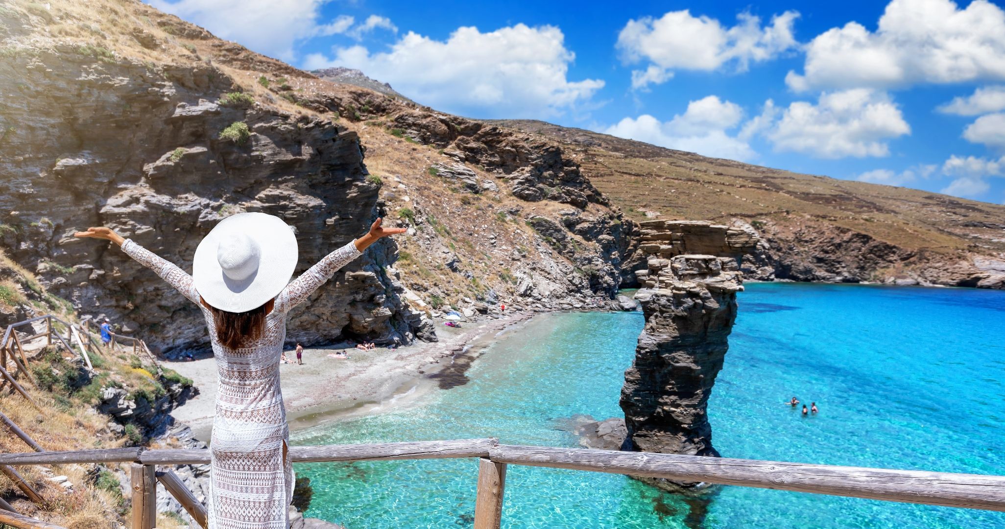 Woman with arms raised overlooking beaches on Andros, Greece