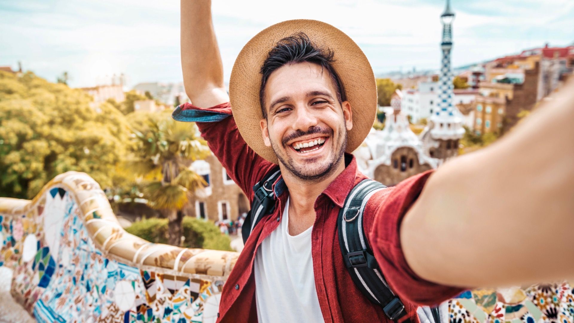 A happy tourist takes a selfie with his smartphone in Park Güell, Barcelona, ​​Spain