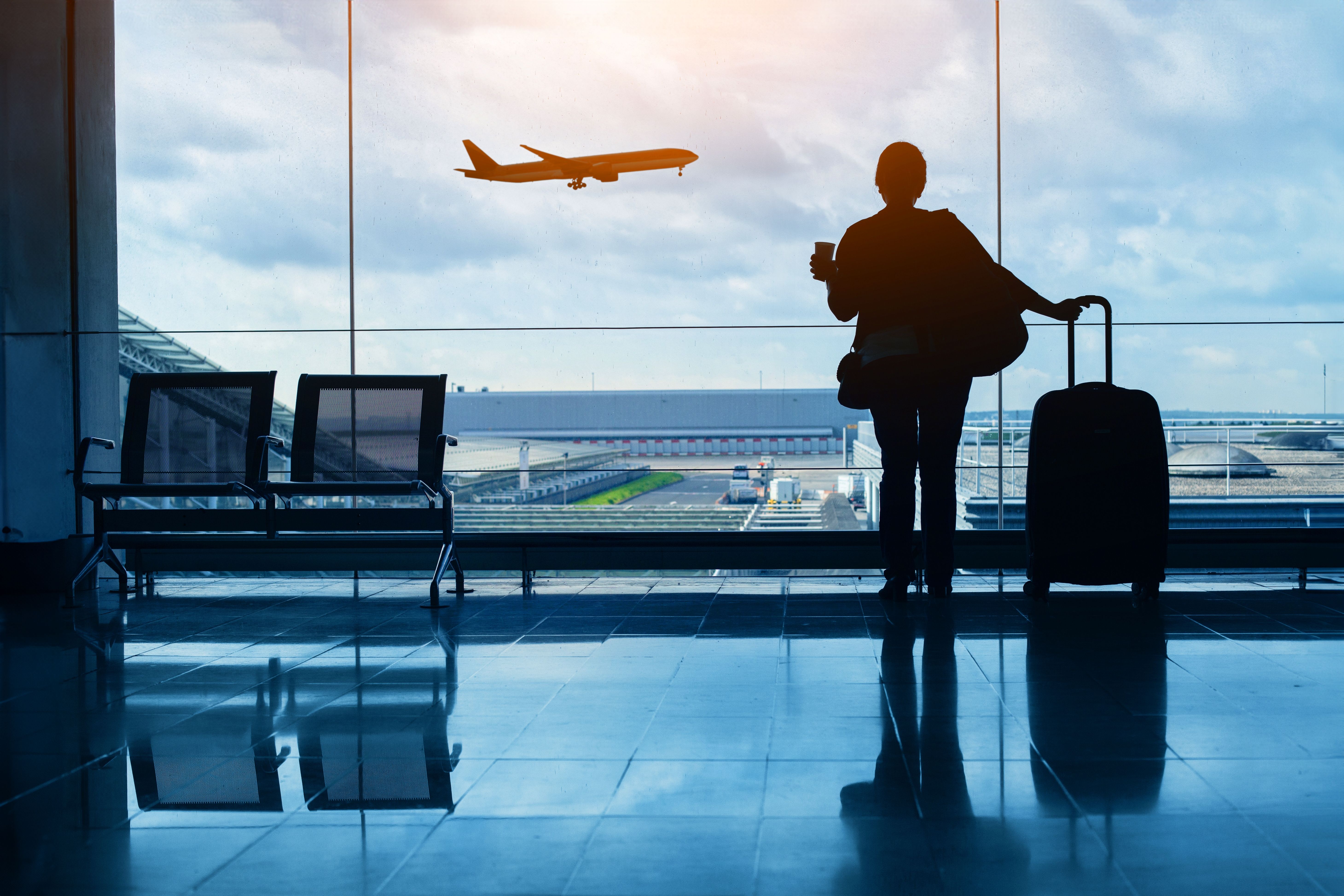 Women standing in departure terminal waiting to board airplane