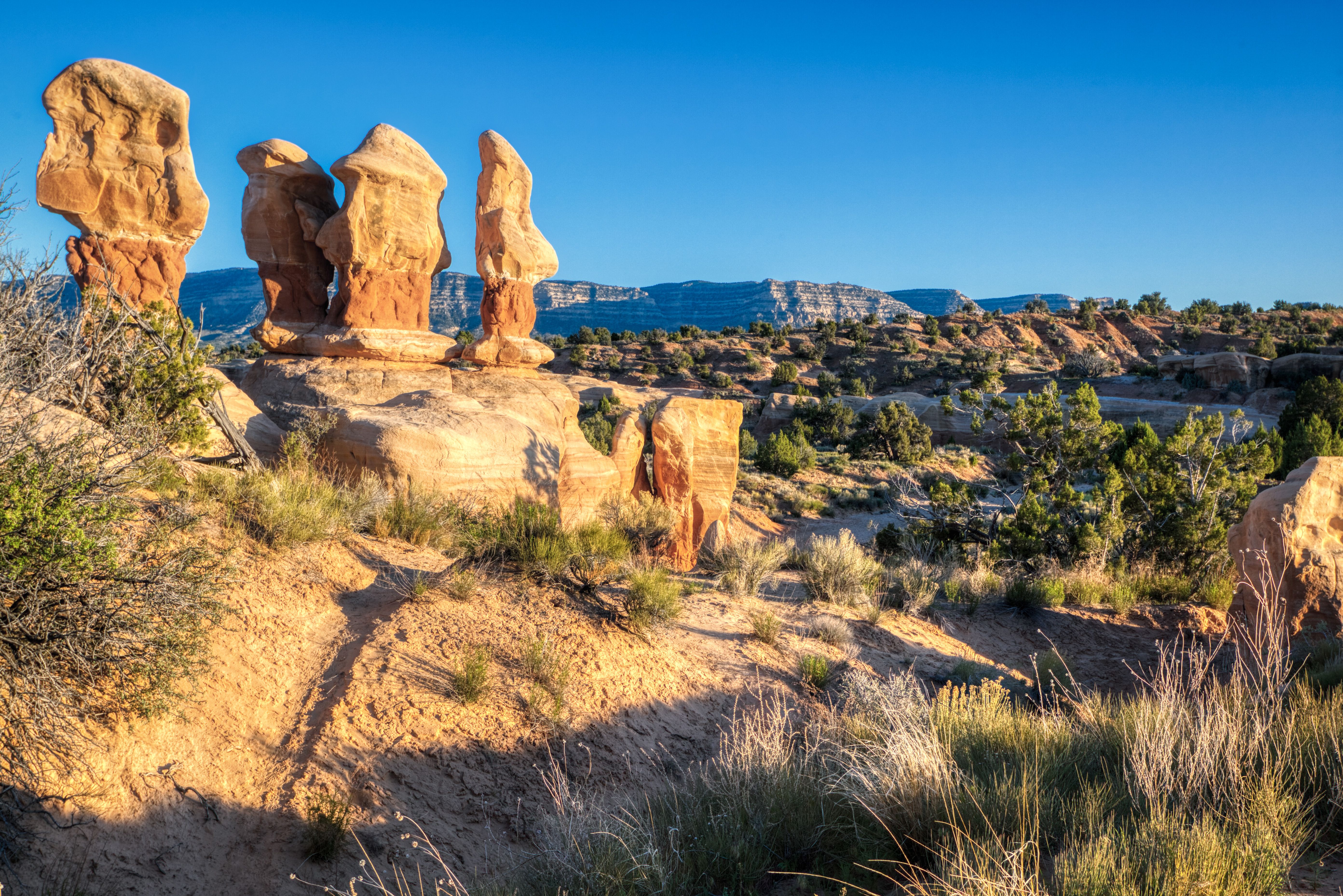 Unique rock formations known as hoodoos are found in Escalante, Utah's Devil's Playground. Four Hoodoos stand watch over the cliffs and mountains of Escalante, Utah.