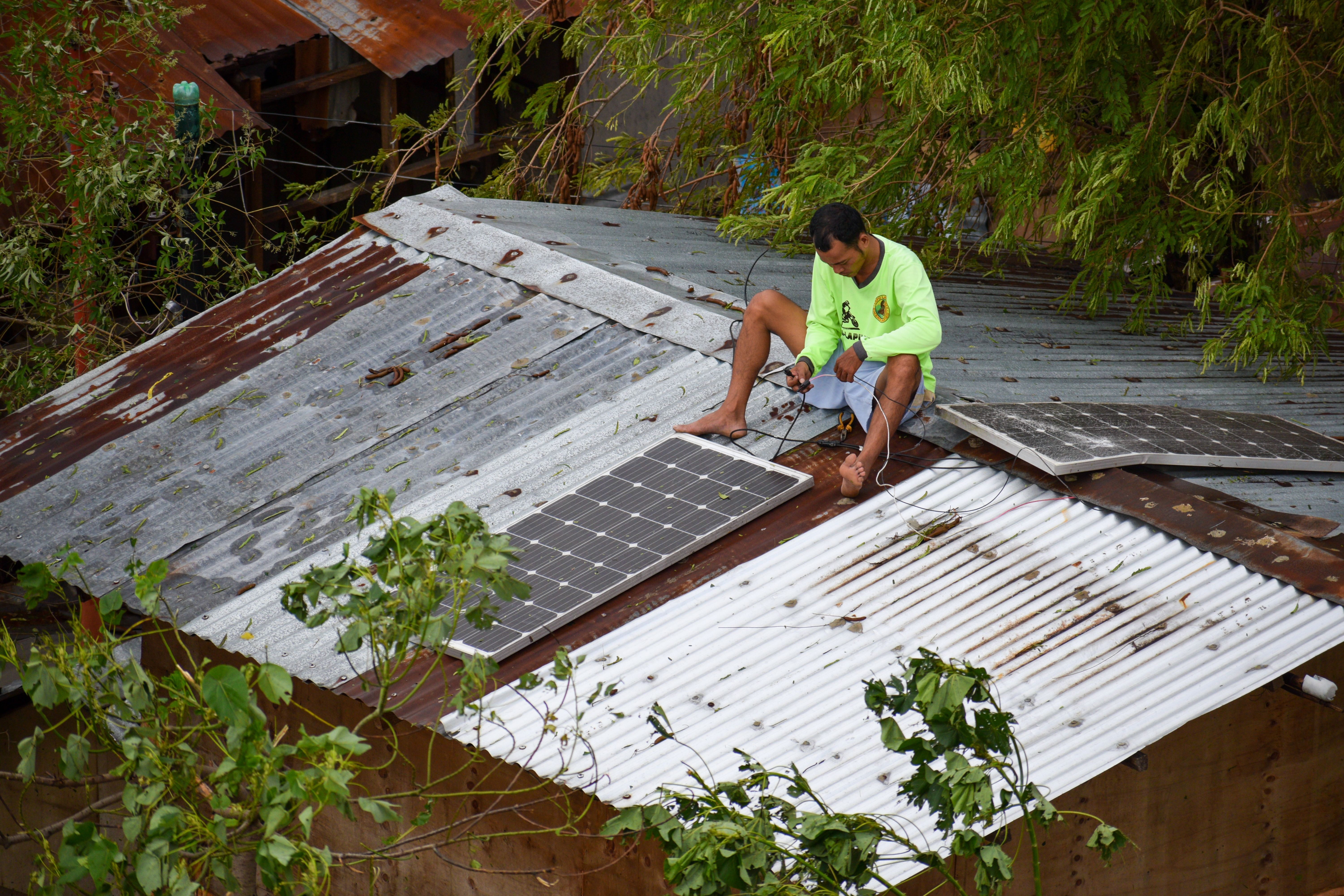 Man on roof - Typhoon aftermath, Philippines - Shutterstock-1