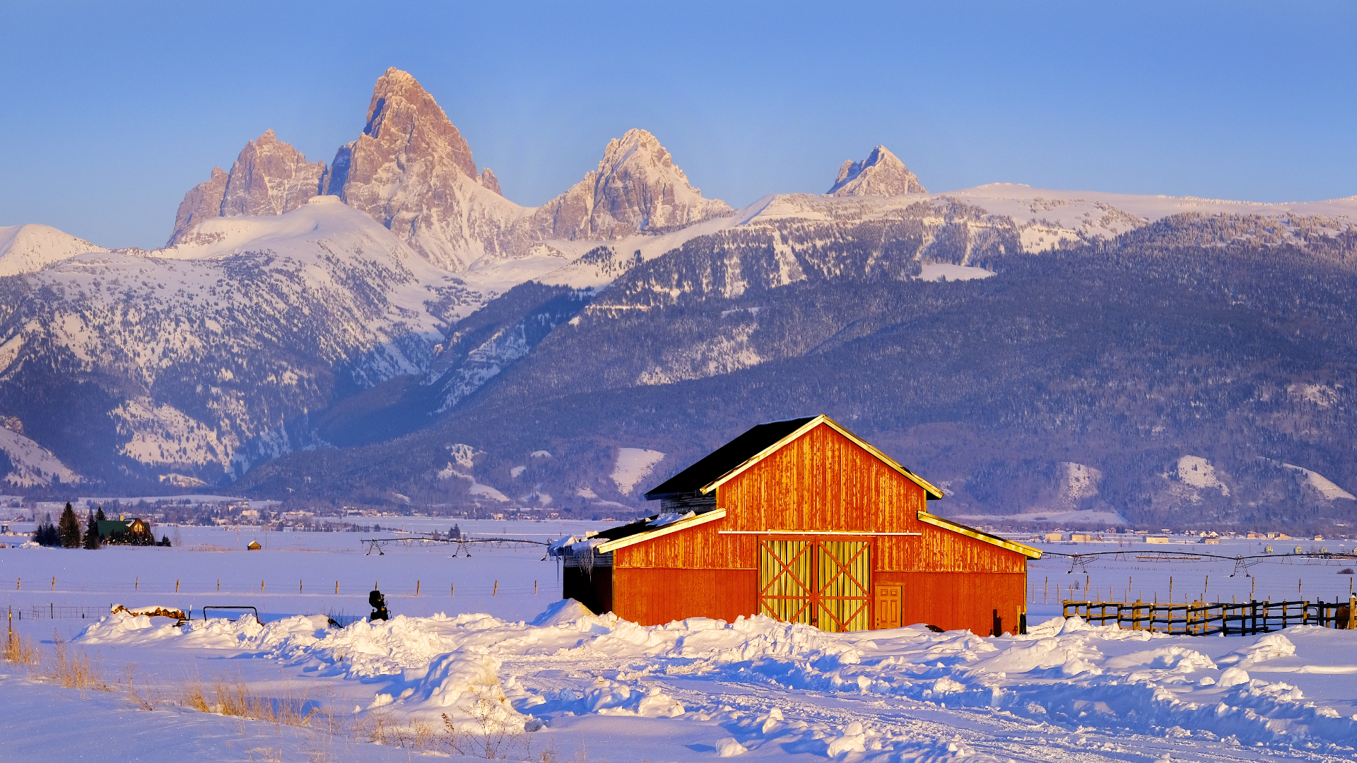 Teton Mountain Range Idaho Side Red Barn in Winter Blue Sky and Forest.