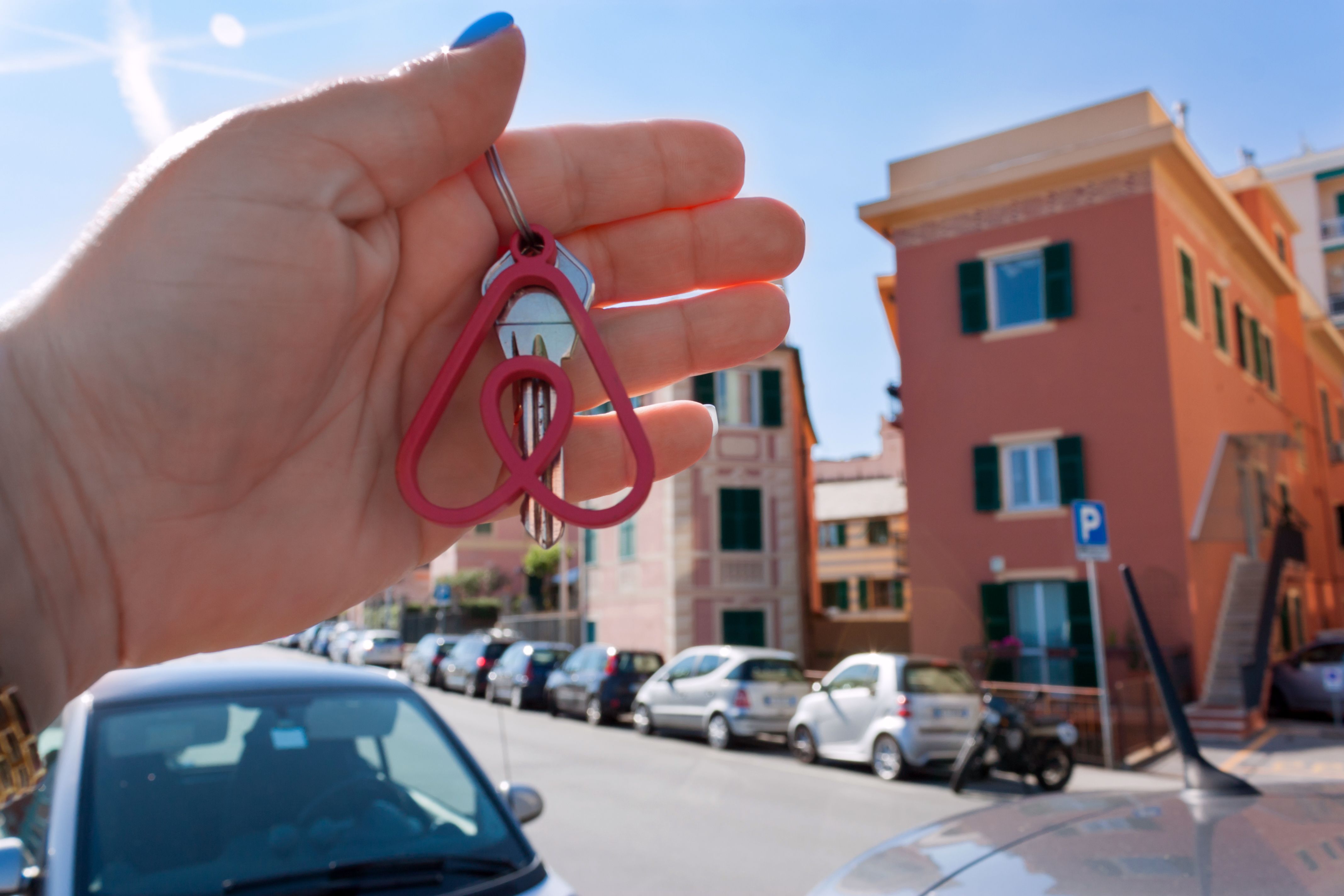 Genova, Italy. May, 2019. Woman holds the key with the logo of a popular company Airbnb.Travel around the world with Airbnb