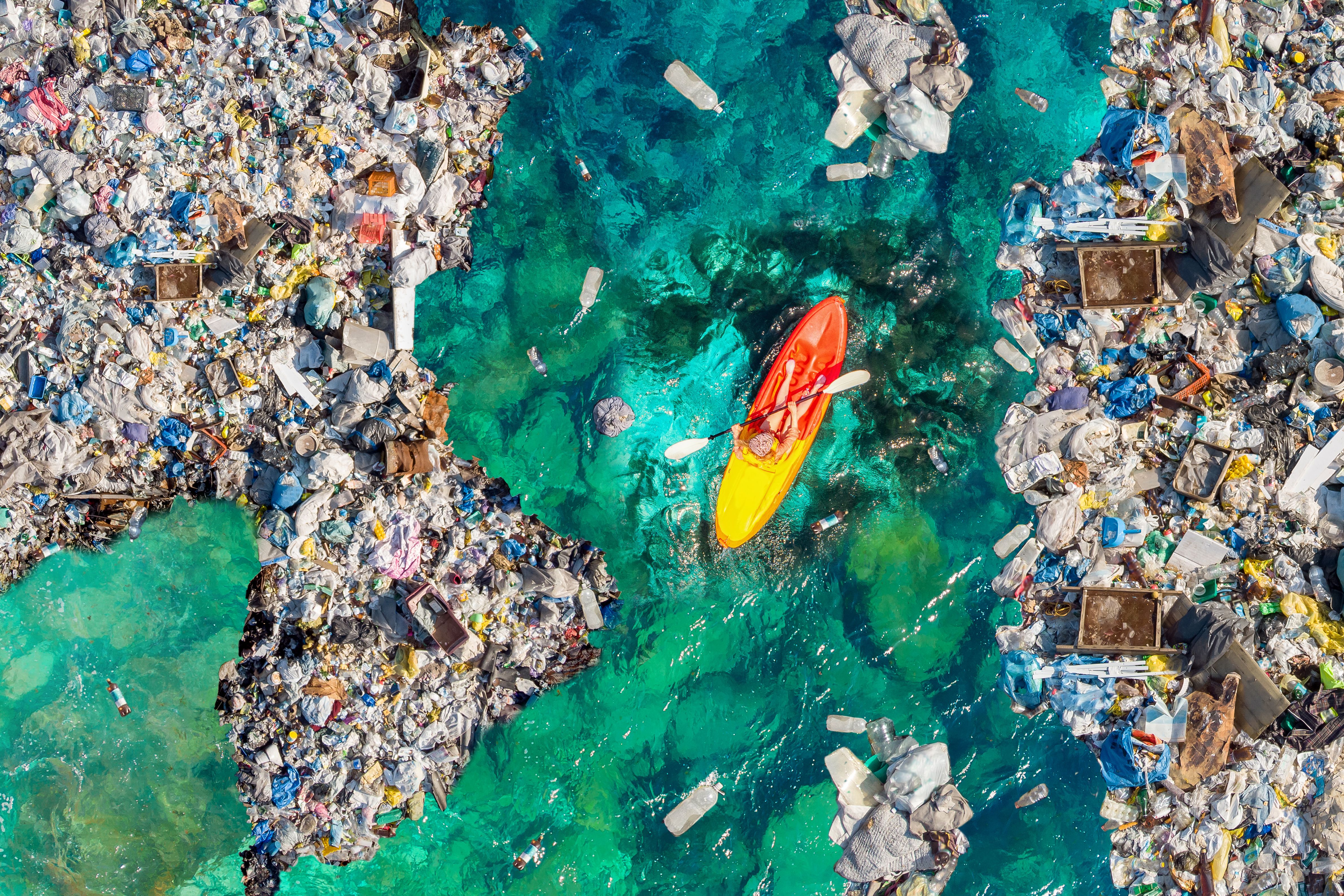Kayak boat boat moves through garbage, garbage and plastic in the sea of blue