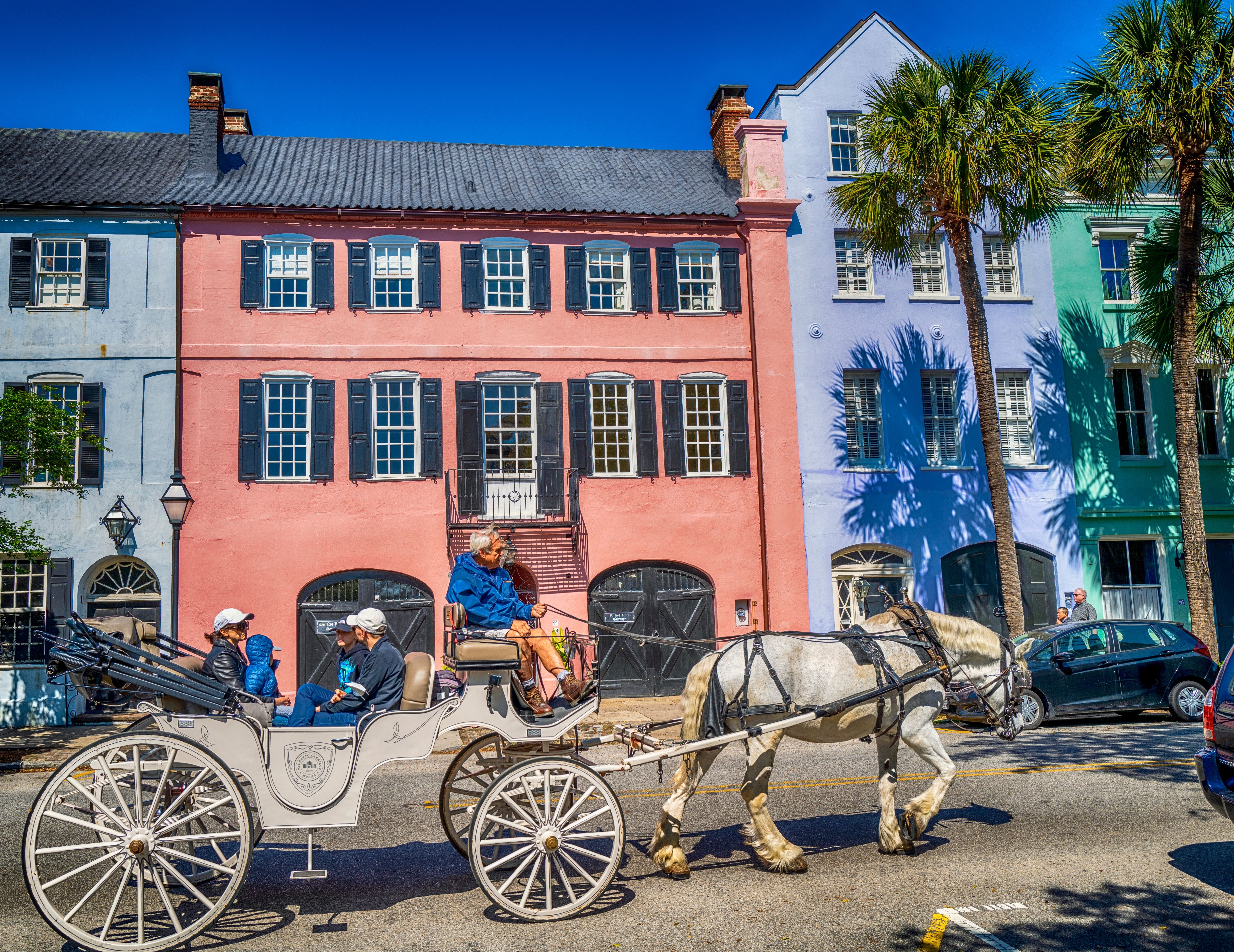 Tourists on a horse and cart in front of the famous Rainbow Row houses in Charleston, SC