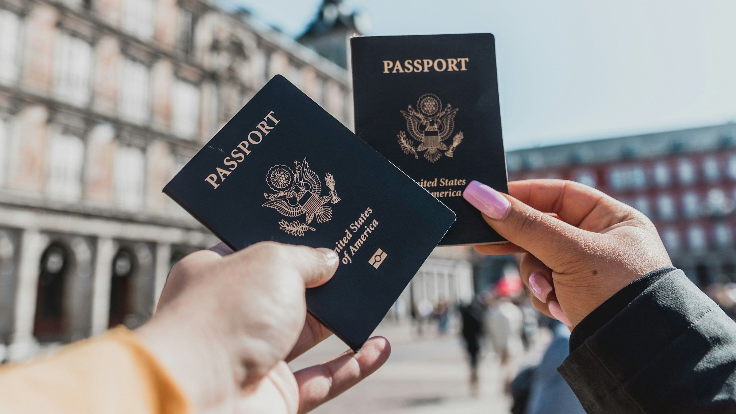 Two hands holding up US passports in Spain