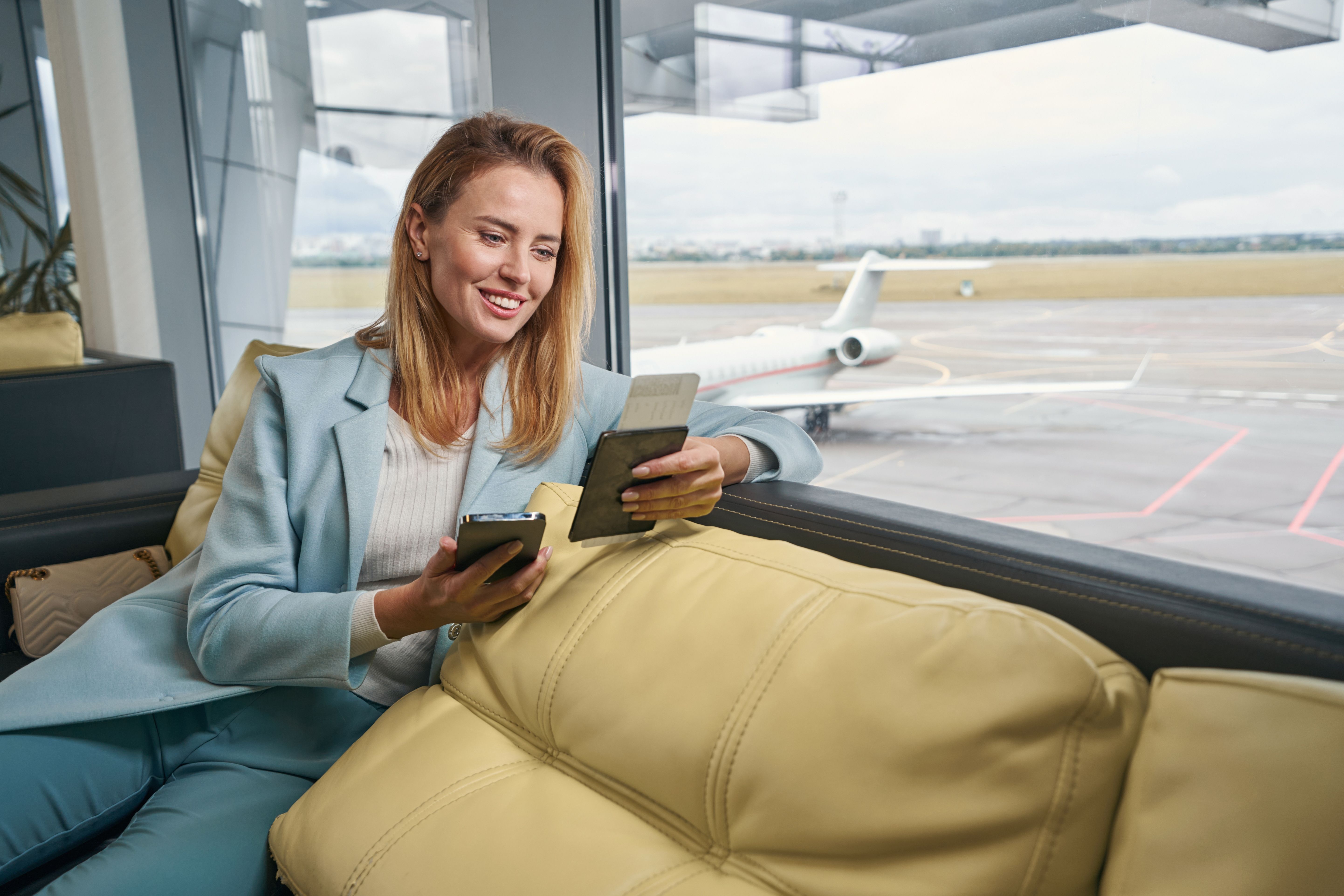 A tourist waiting for her flight in an airport lounge overlooking the tarmac.