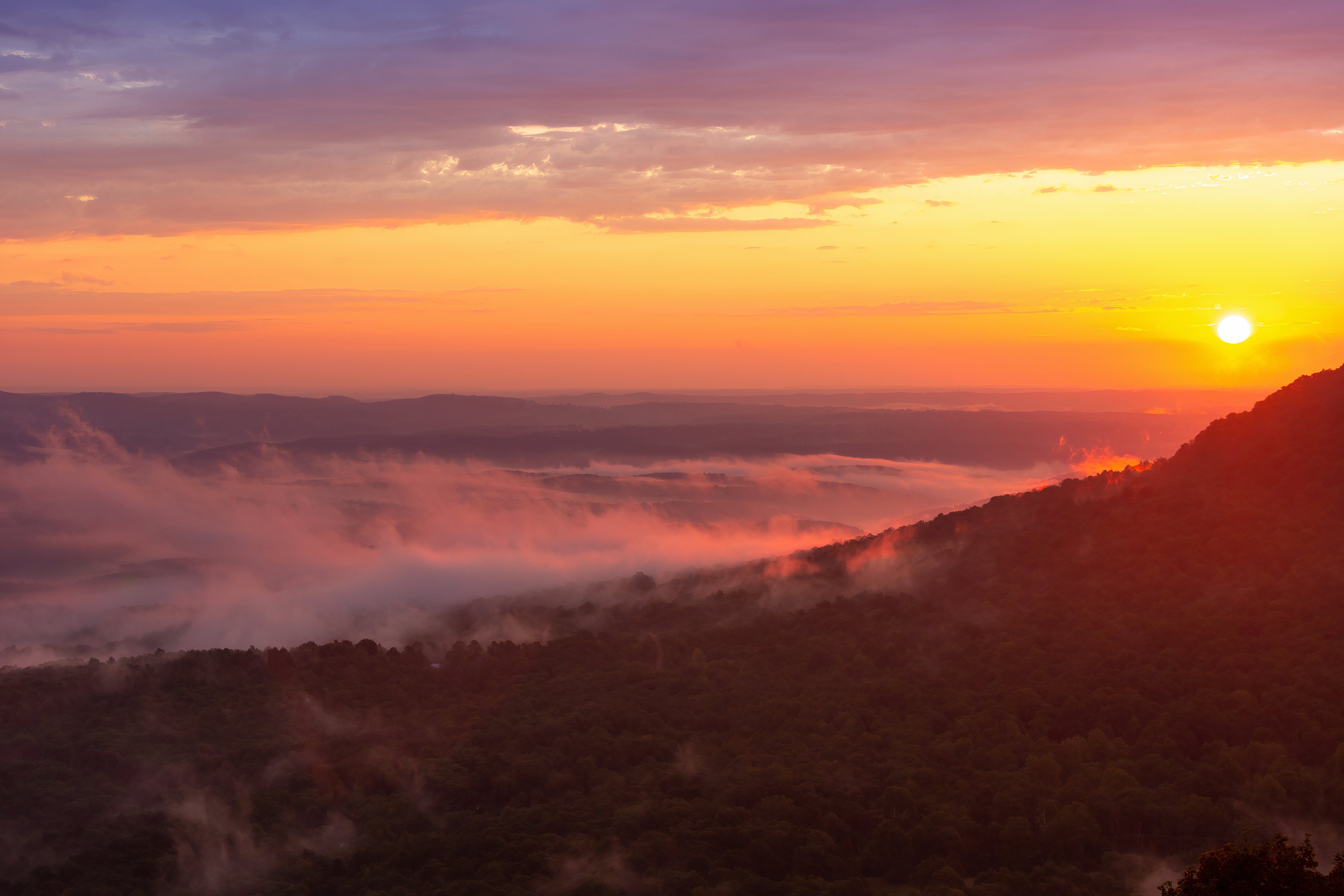 Colorful morning sunrise with golden glowing fog clouds over mountains at Arkansas Grand Canyon Scenic Point Overlook