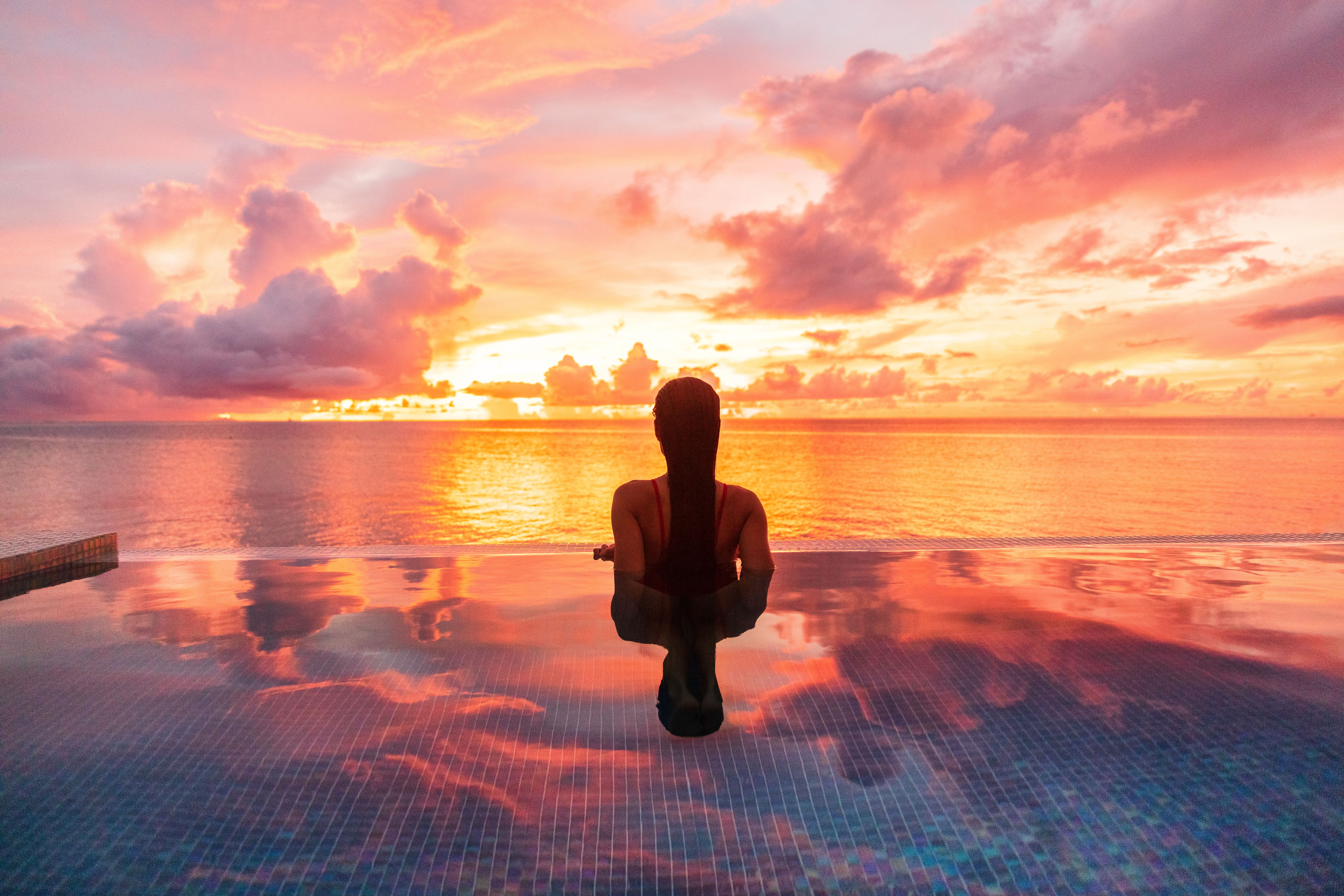 Woman in infinity swimming pool overlooking the Mexican ocean
