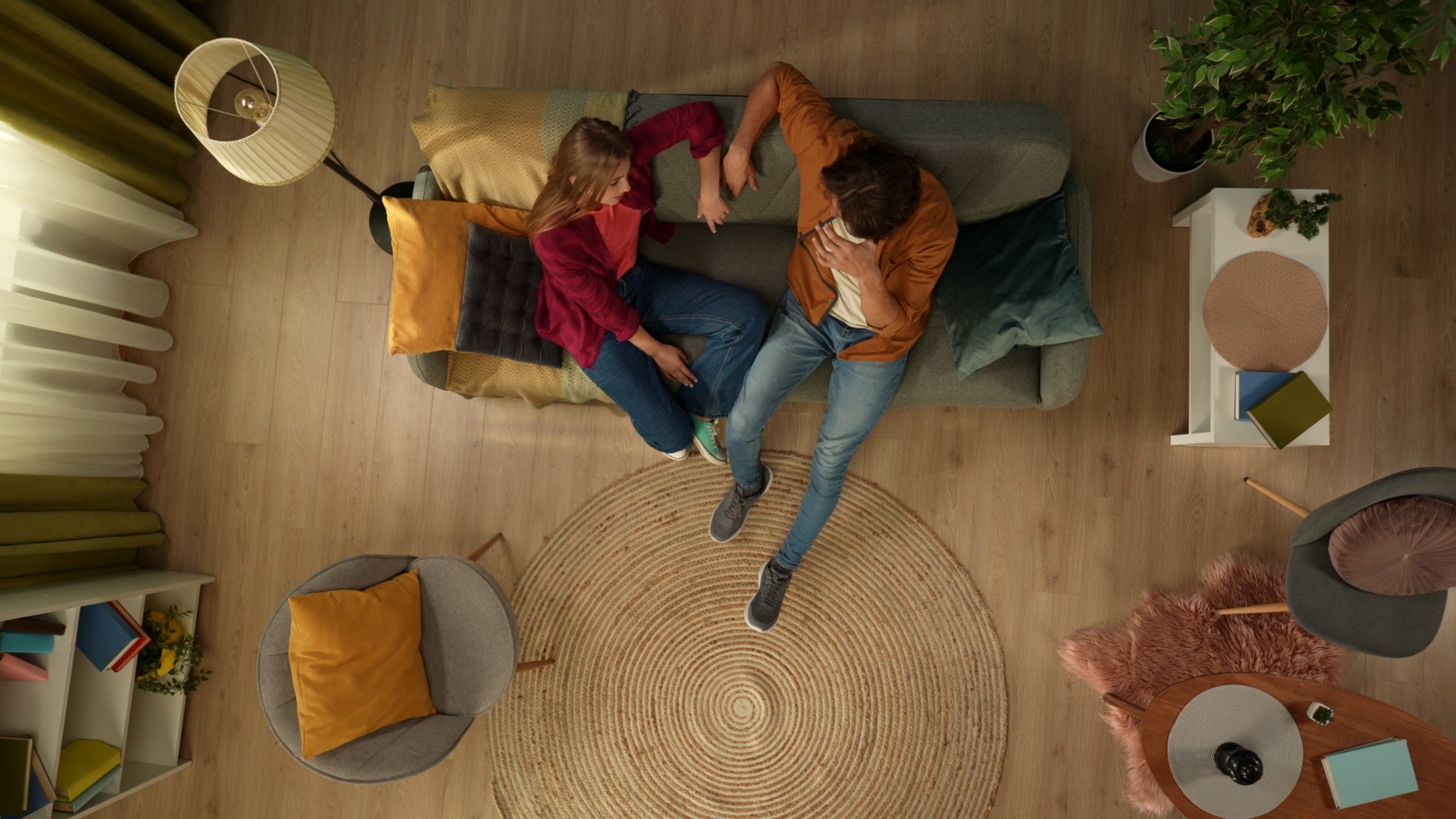 The hidden camera catches a young couple into the frame. They sit on the couch together, talk to each other warmly and hold their hands.