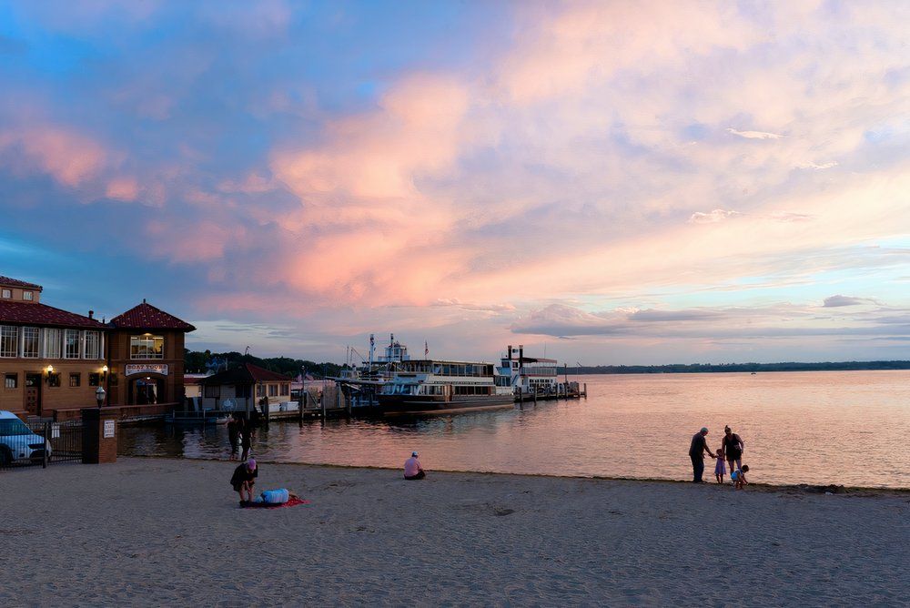 People gather at Riviera Beach near Lake Geneva, showing the boat docks during a gorgeous pinky and cloudy sunset