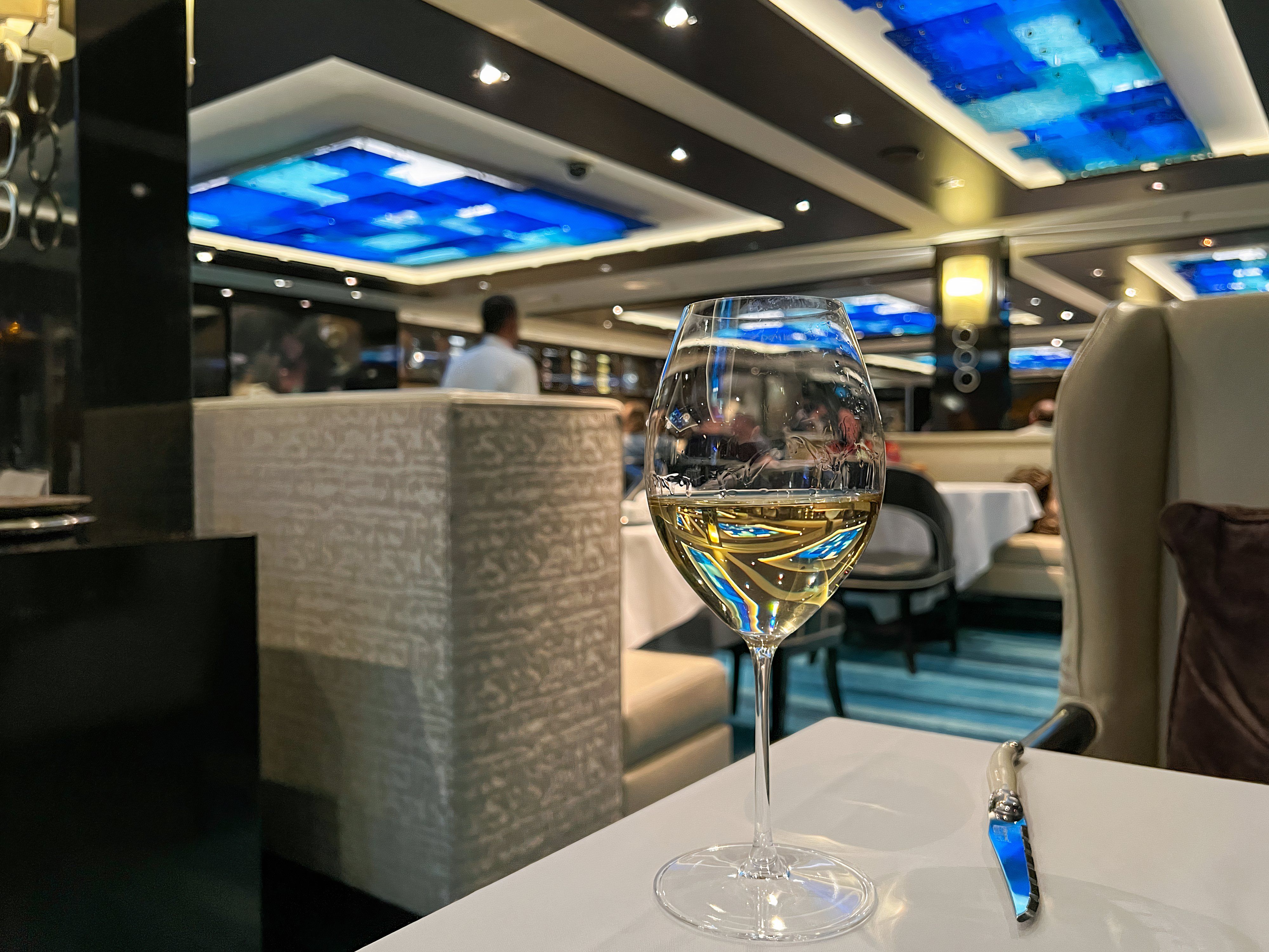 A freshly poured glass of Chardonnay wine in The Haven dining room on the Norwegian Escape cruise ship