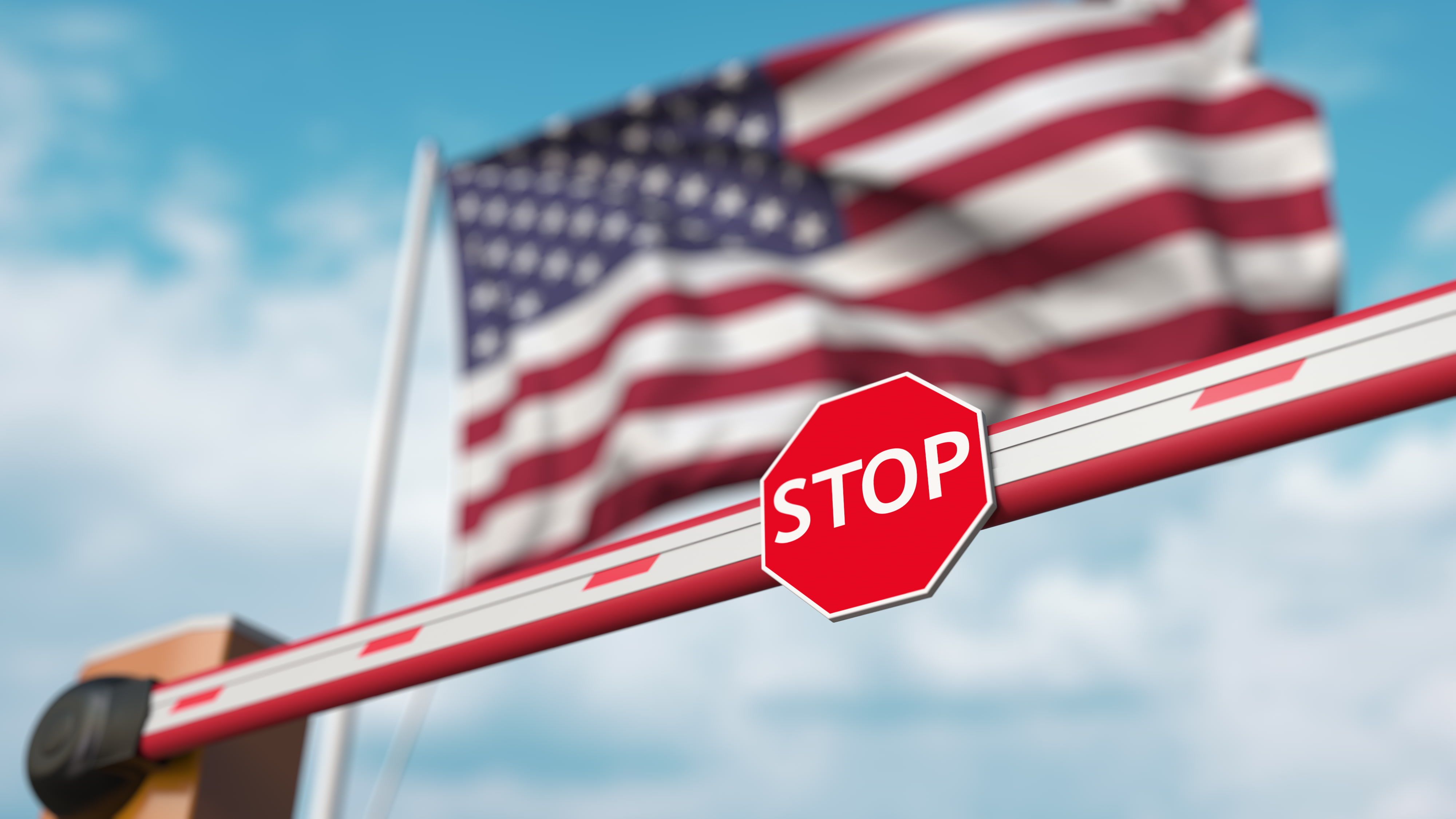 Closed boom barrier with stop sign in front the American flag