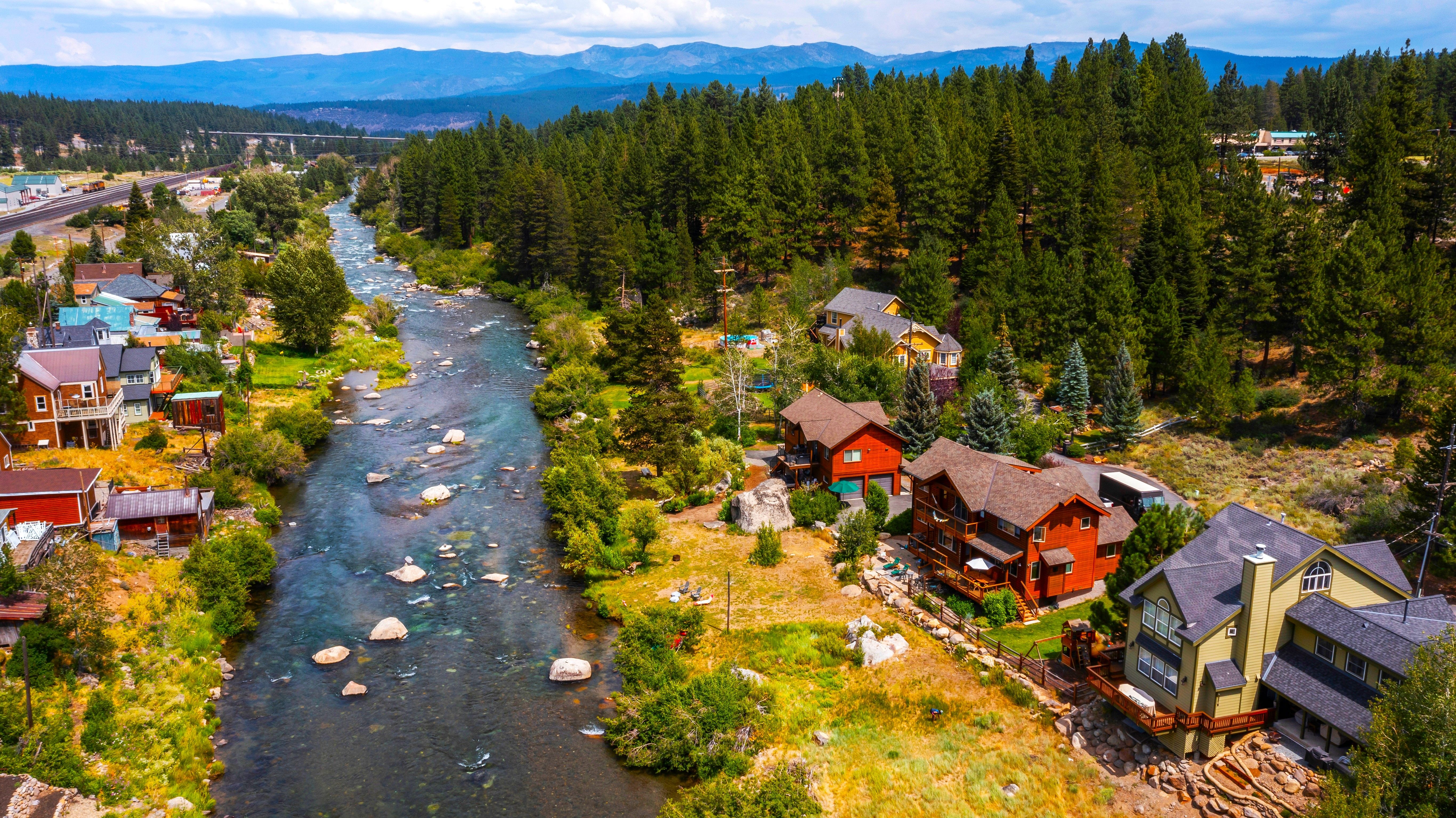 View of houses by the river with trees and mountains in the background in Truckee, California, CA USA