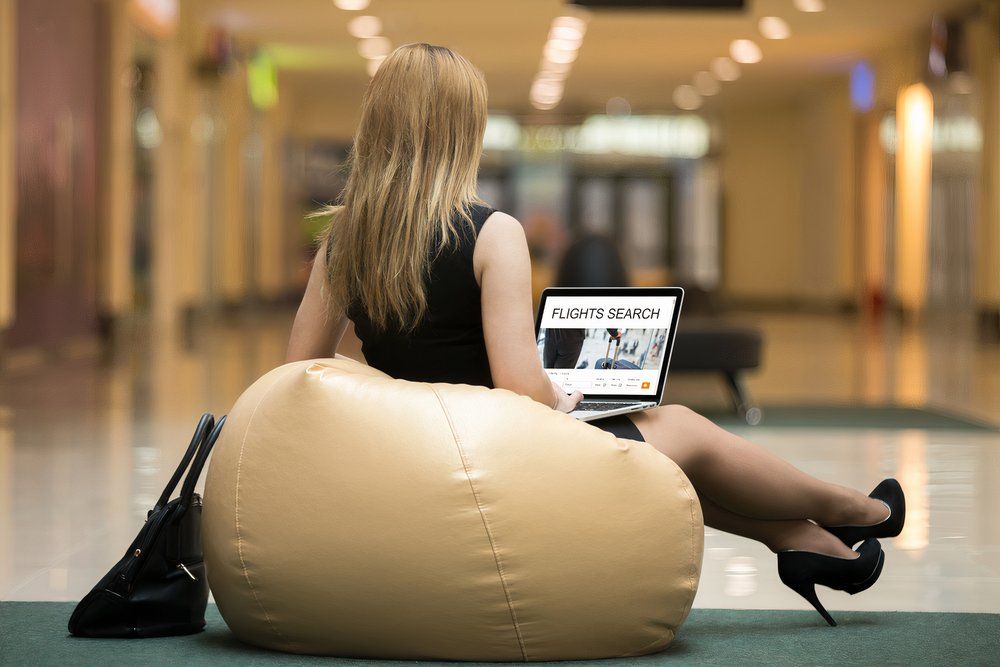 A woman wearing stilettos, sitting on a bean bag, in search of a flight