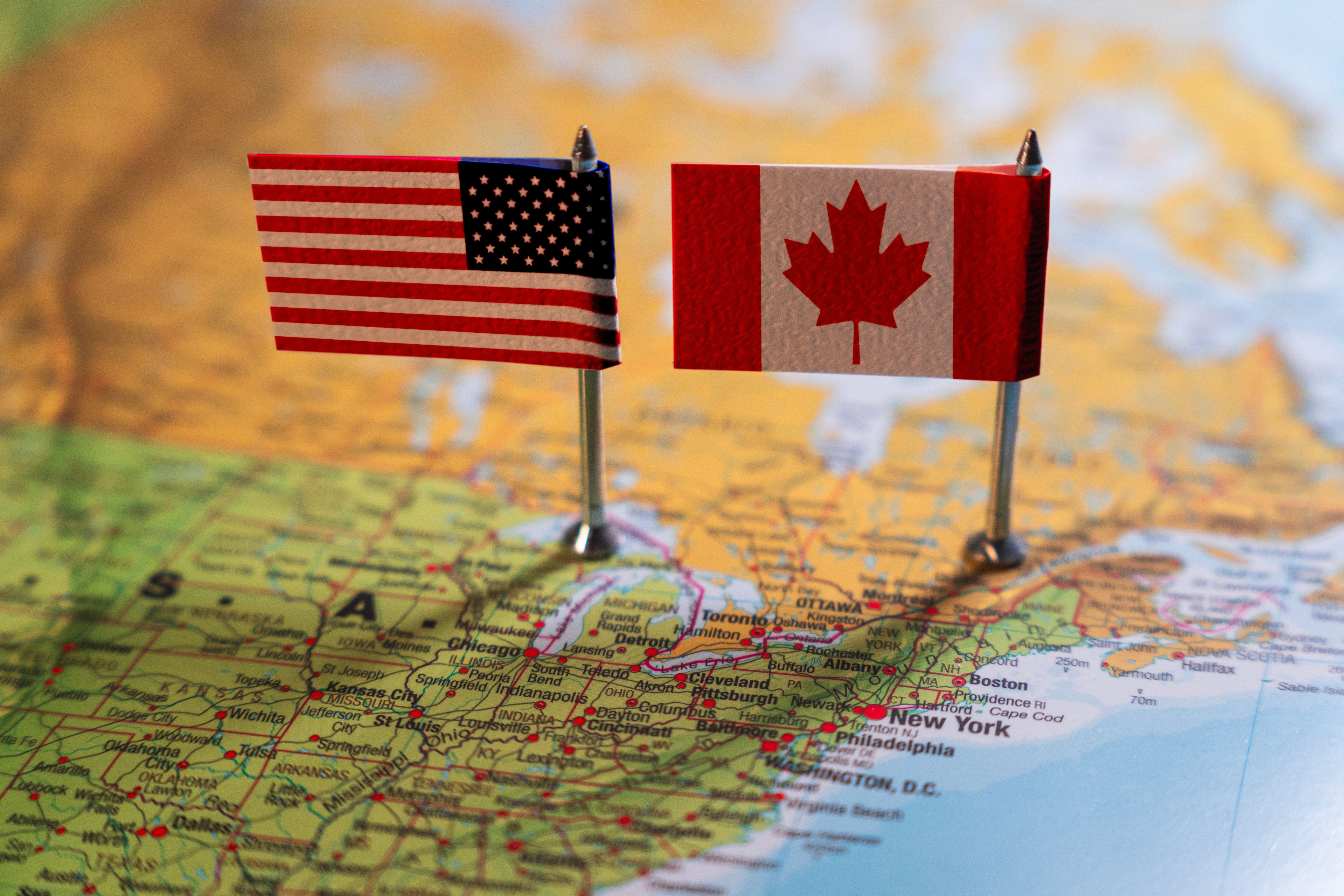 United States and Canada flags placed on a map, representing the close relationship and shared border between the two countries.