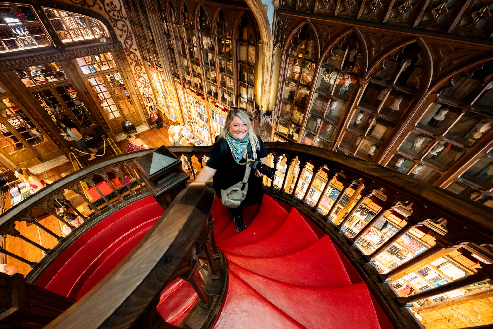 Woman walks up the spiral staircase in Livraria Lello, the library said to inspire Harry Potter books