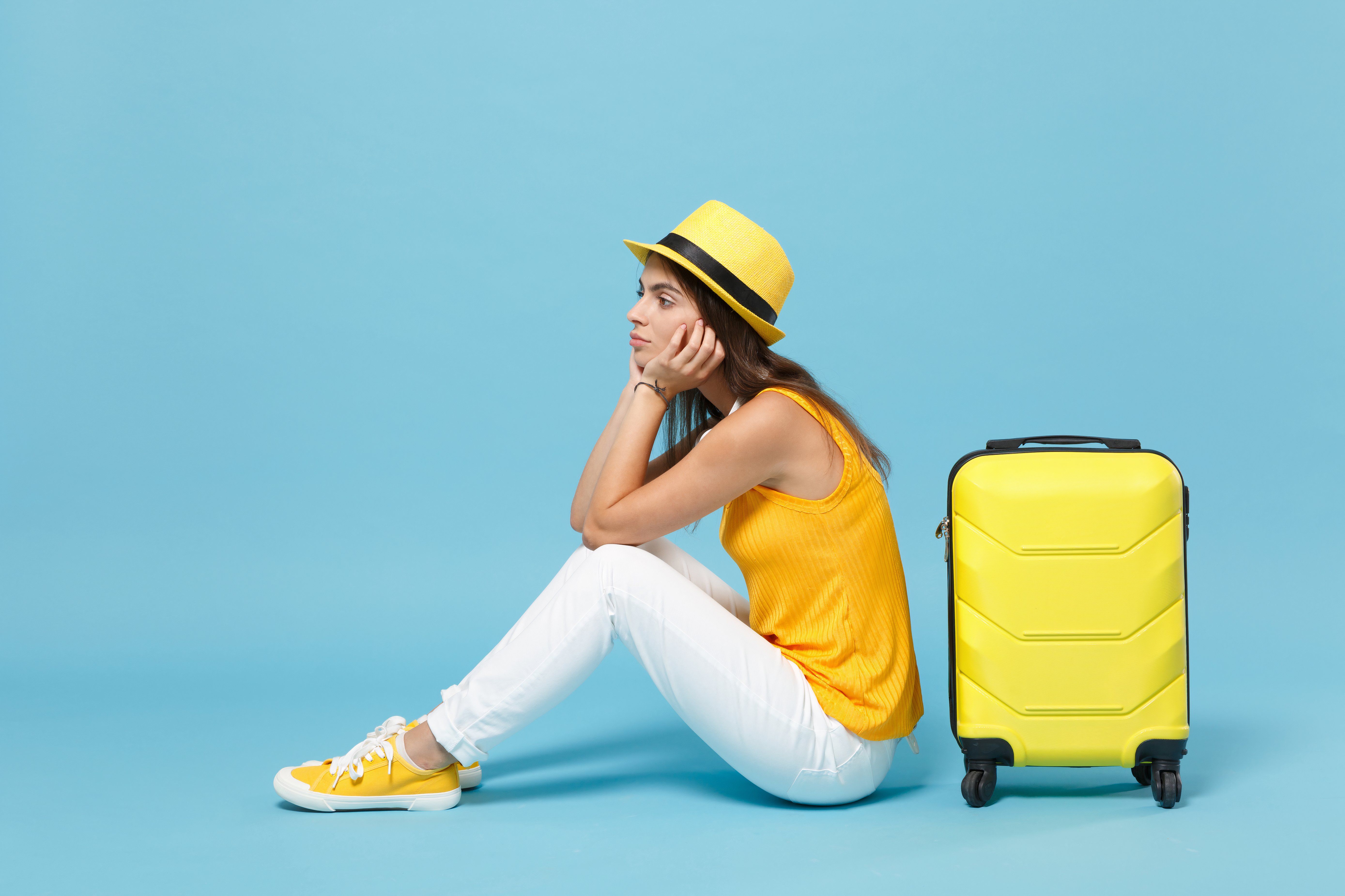 Upset tourist woman in summer casual clothes sit on suitcase put hands on head 