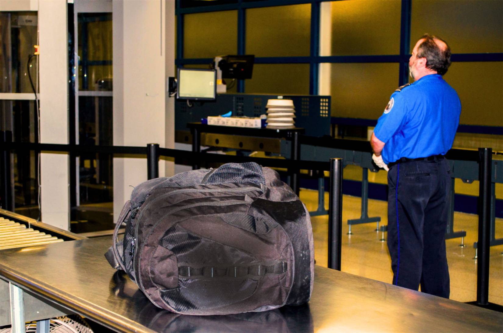 A TSA worker stands by while an unattended bag waits to be claimed at an American airport