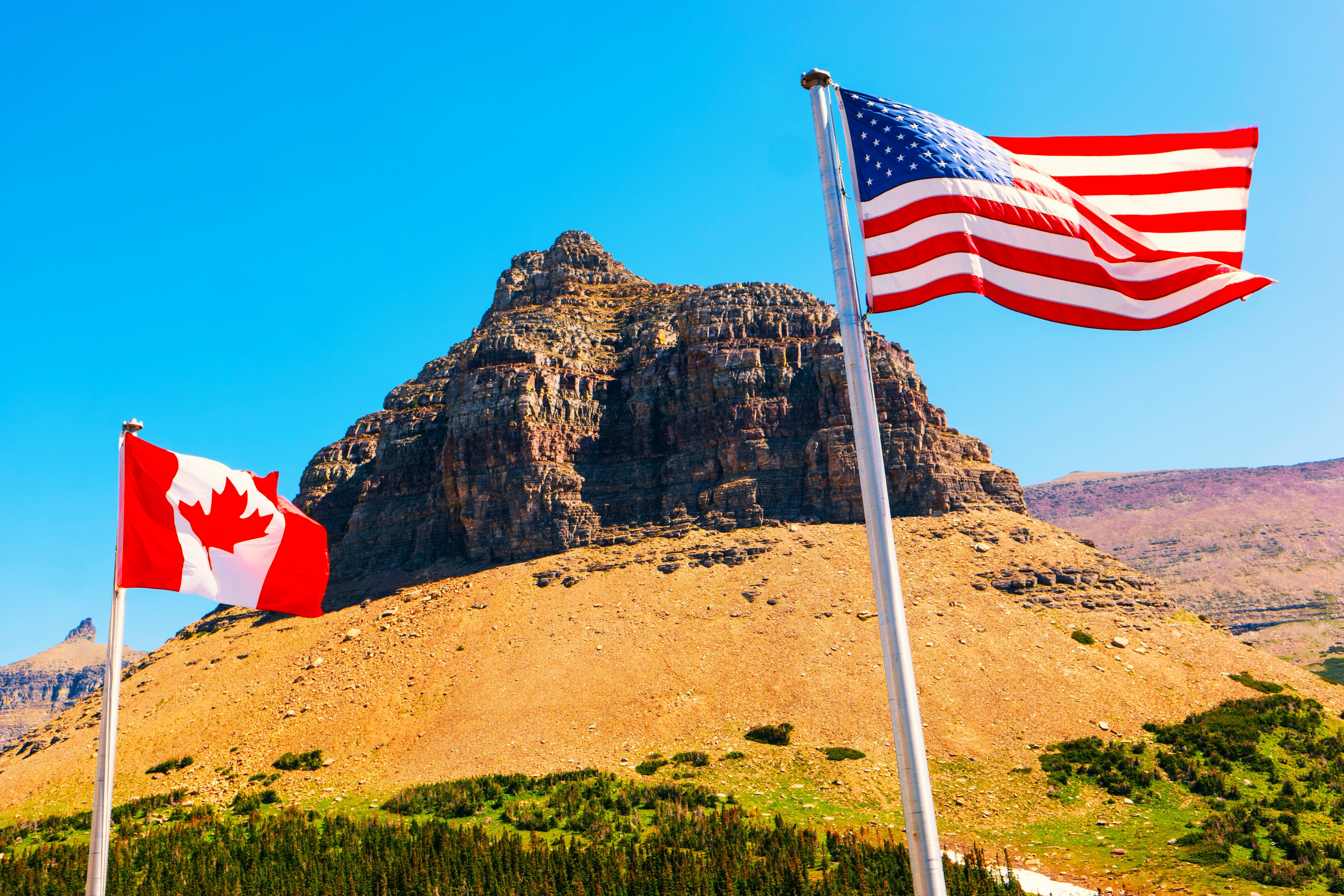 The American flag next to a Canadian flag at Pollock Mountain in Glacier National Park, Montana, MT, USA, which borders the United States of America and Canada