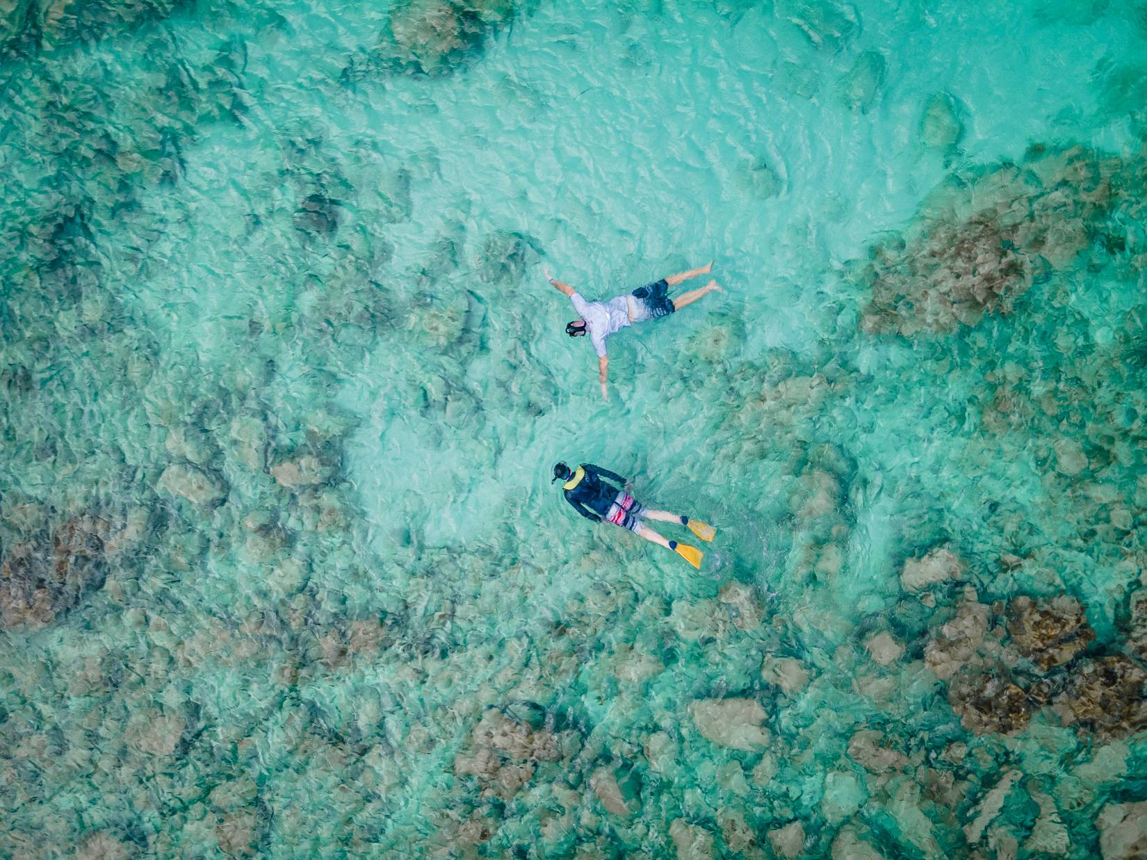 An aerial photo of two people snorkelling in shallow turquoise water at Eagle Beach, Aruba